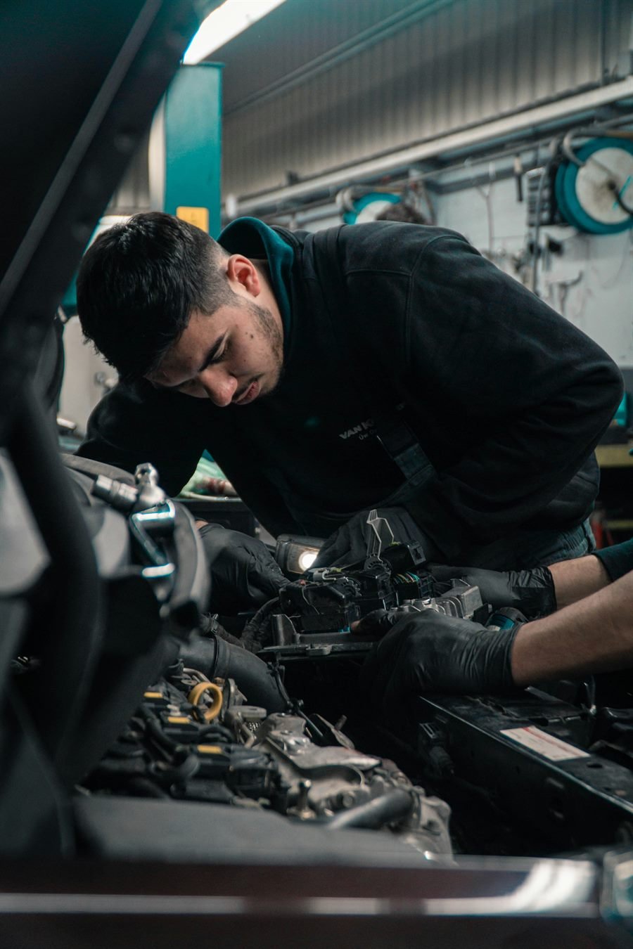 Mobile mechanic checking a vehicle under the hood in metro Atlanta